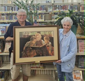 A framed print gifted to the Library from W.D. and Patty as they spend their last day at Wilkins Myrick Frames & Fine Arts before they turn the page and start a new chapter in their lives, called retirement.
